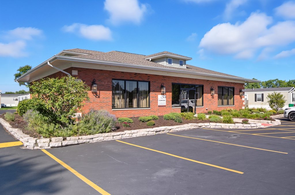 Single-story brick office building with large windows, surrounded by landscaped plants and an empty parking lot.