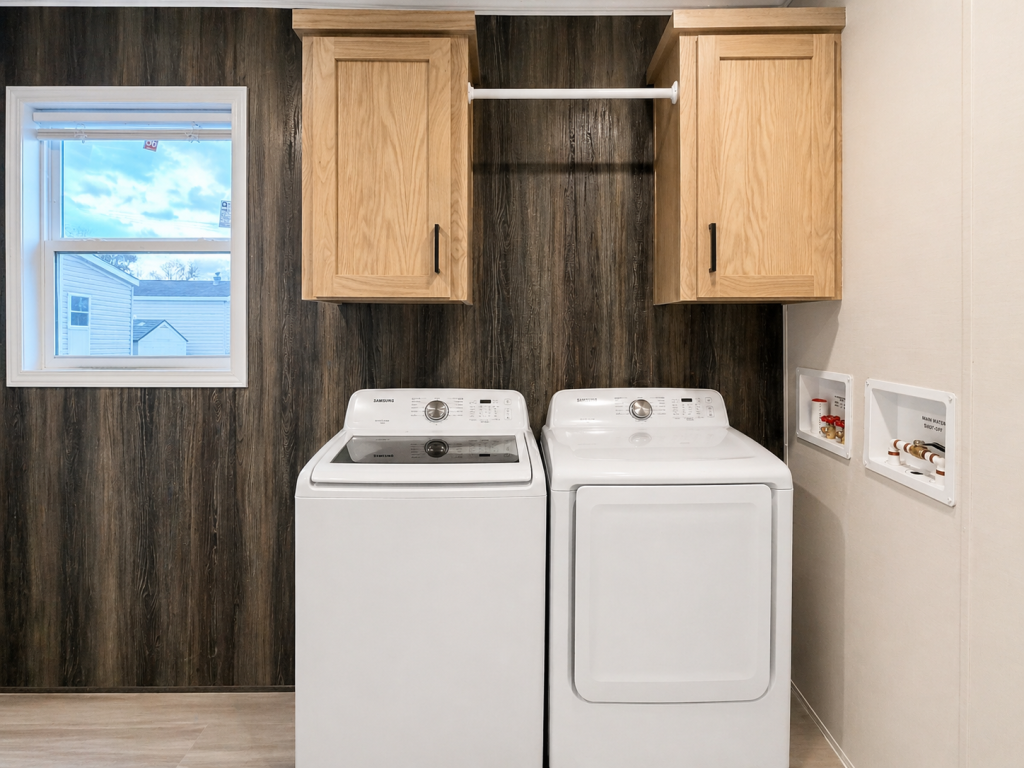 Laundry room with a washer, dryer, wooden cabinets, window, and exposed water hookups on the right wall.