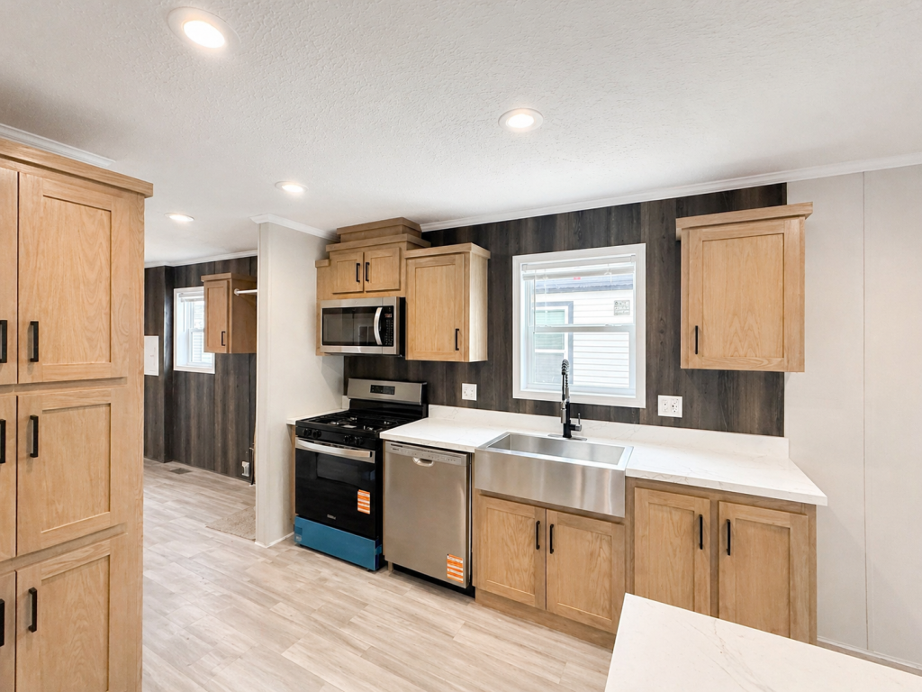 Modern kitchen with wood cabinets, stainless steel appliances, farmhouse sink, and white countertops.