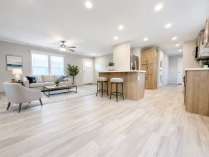 Open-concept living room and kitchen with modern decor, light wood floors, and neutral-colored furniture.